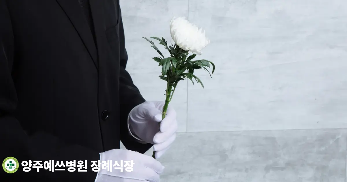 흰 국화를 들고 있는 상복 차림의 조문객